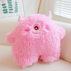 Playful and fun monster plush pillow displayed on a sofa