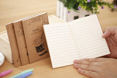 person writing in a vintage kraft notebook