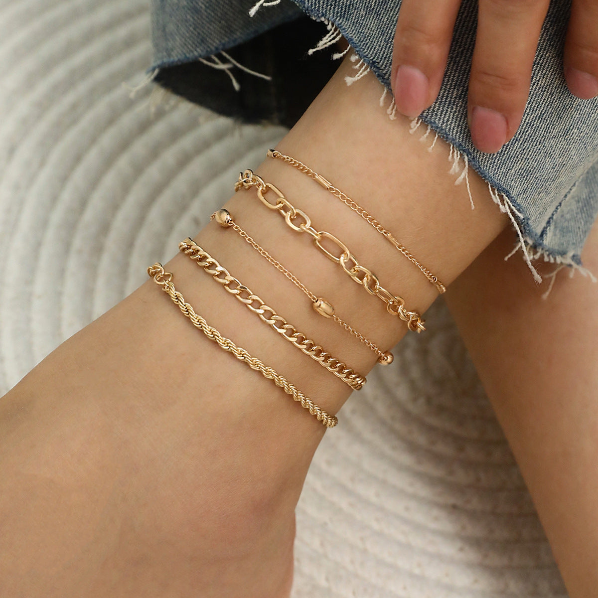 Woman styling multiple anklets for a layered look