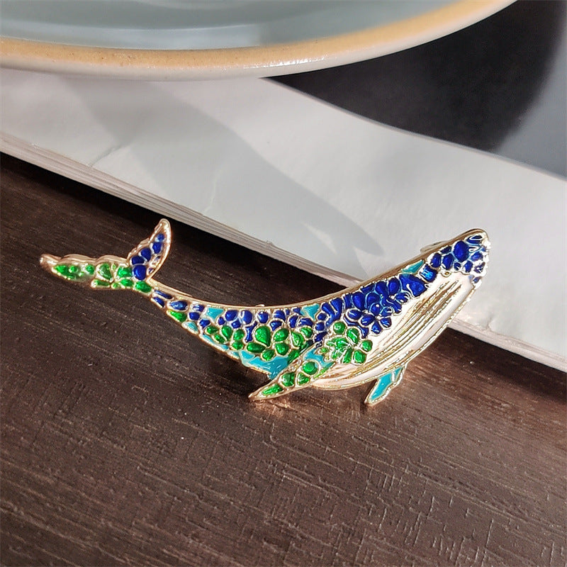 Whale and dolphin brooch laid flat on a surface