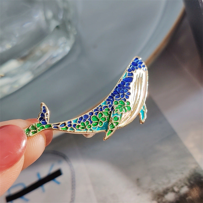 Whale and dolphin brooch laid flat on a surface