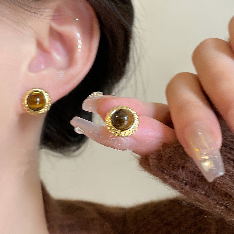 Close up of elegant metal earrings with tiger eye stones