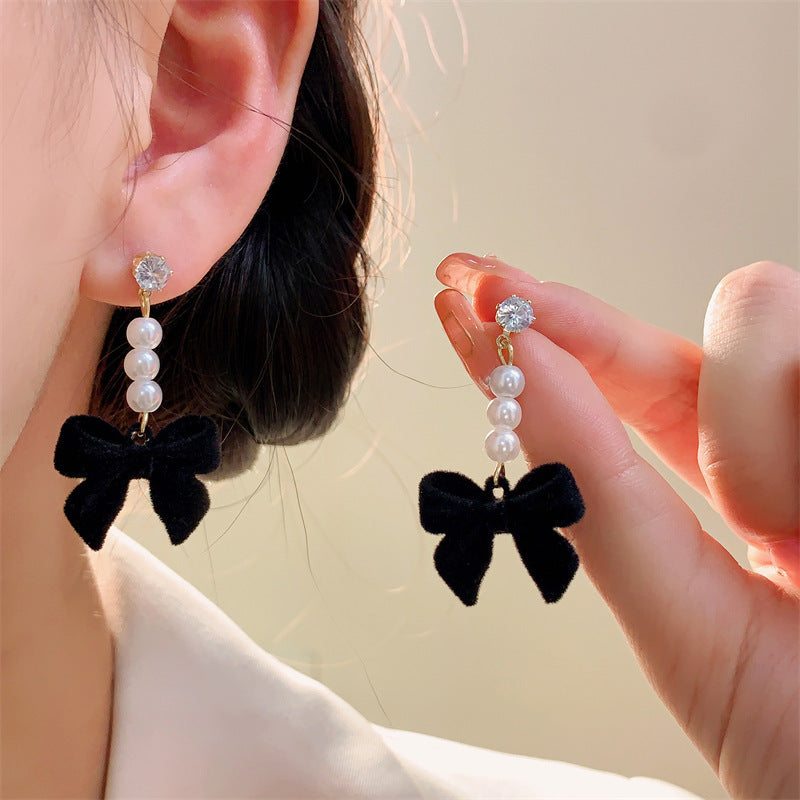 Red velvet bow earrings shown with winter outfit