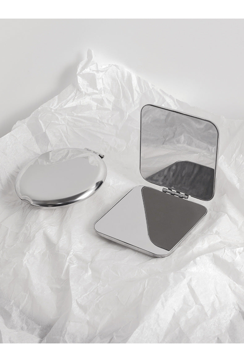 Stainless steel portable makeup mirror on table